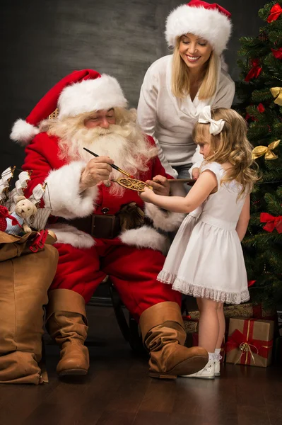 Santa claus siedzi w domu z rodziną - mała dziewczynka i jej matka — Zdjęcie stockowe