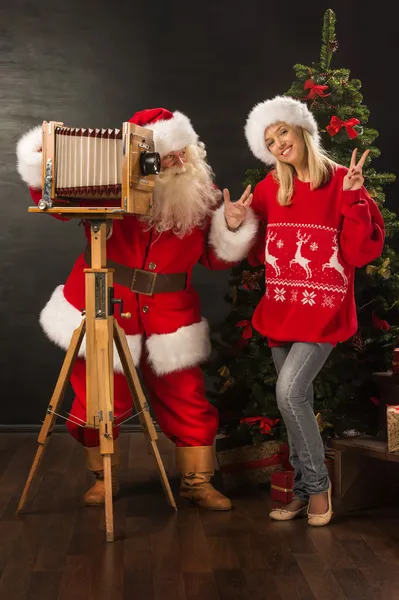 Santa Claus taking picture of cheerful woman with old wooden camera — Stock Photo, Image