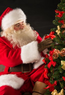 Noel Baba, karanlık odada Noel ağacı süsleme