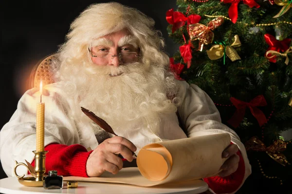 Papai Noel sentado em casa e escrevendo uma carta — Fotografia de Stock