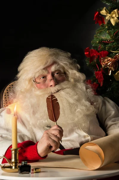 Papá Noel sentado en casa y escribiendo una carta — Foto de Stock