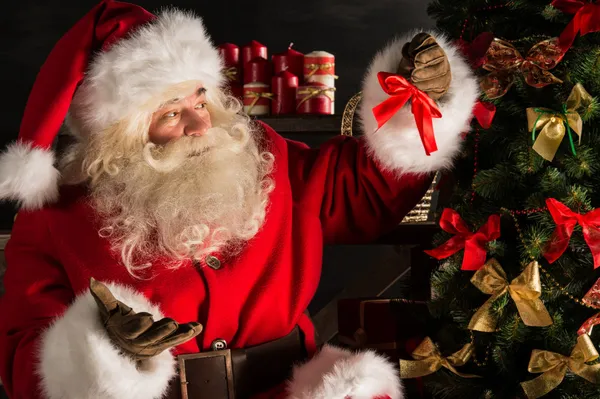 Santa Claus decorating Christmas tree in dark room — Stock Photo, Image