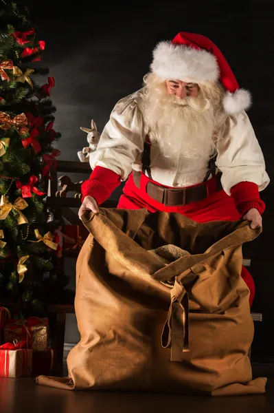 Papai Noel abrindo seu saco e levando presentes — Fotografia de Stock