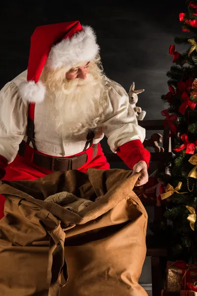 Papai Noel abrindo seu saco e levando presentes — Fotografia de Stock