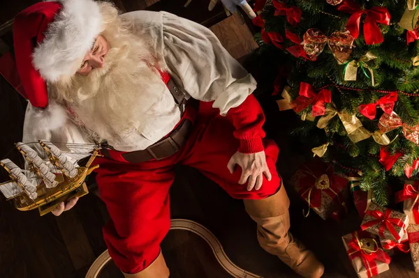 Санта-Клаус дома играет с новыми игрушками под Рождество — стоковое фото