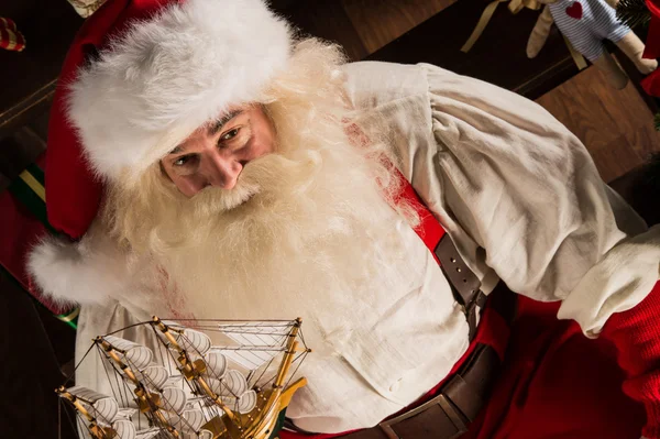 Papá Noel en casa jugando con juguetes nuevos cerca del árbol de Navidad — Foto de Stock