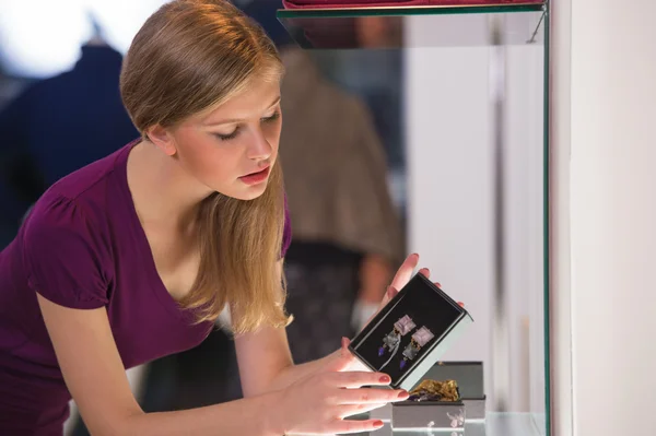 Young woman looking at the shop showcase and taking accessories — Stock Photo, Image