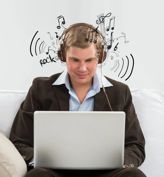 Jovem homem de negócios ouvindo música e trabalhando em seu rastro — Fotografia de Stock