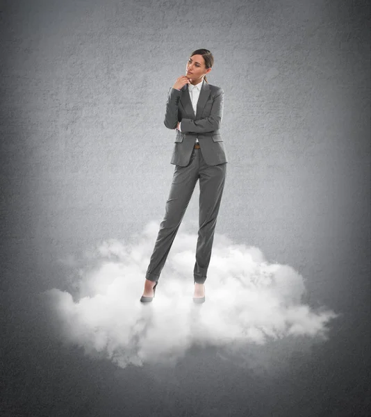 Bir bulutun üzerinde duran genç iş kadını — Stockfoto