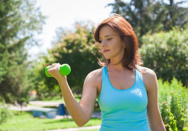 Женщина делает упражнения с гантели на открытом воздухе — стоковое фото