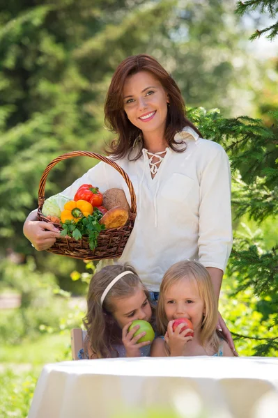 Mère souriante et deux filles s'amusent dans un pique-nique — Photo