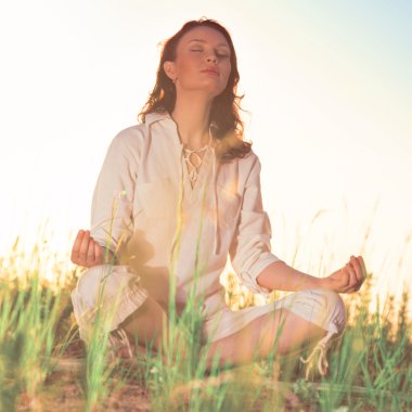 Yeşil çimlerde yoga yapan kadın.