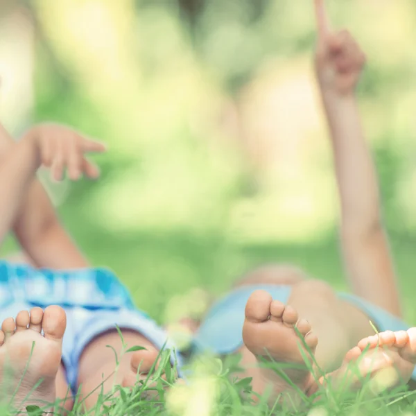 Kinder liegen auf Gras und zeigen in den Himmel — Stockfoto