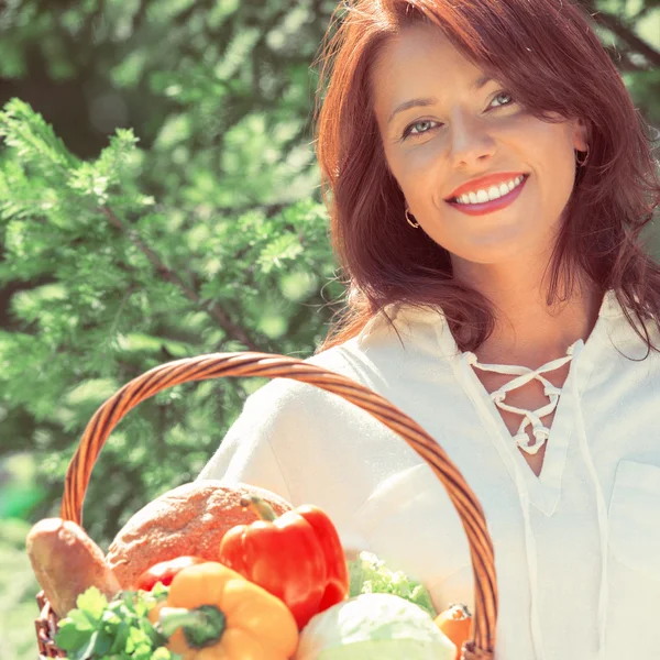 Kvinna anläggning korg med grönsaker — Stockfoto