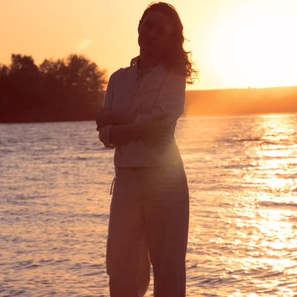Mladá žena chůze po pláži při západu slunce světle — Stock fotografie