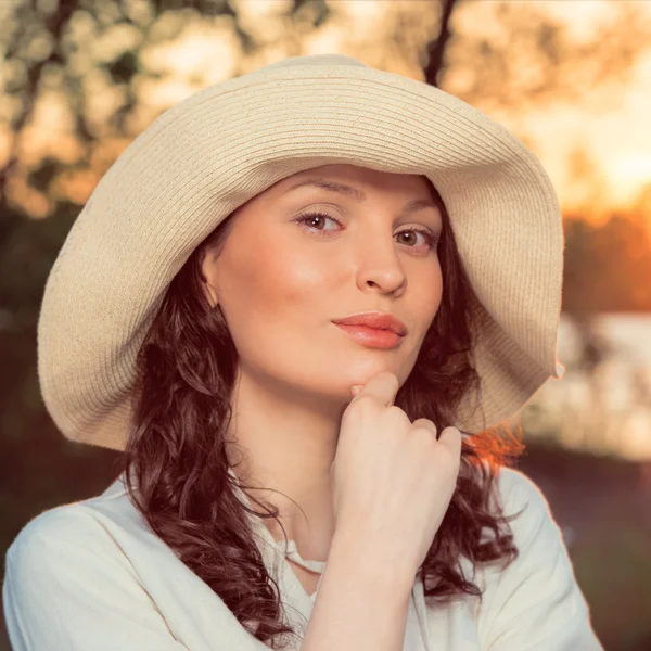 Mujer joven y hermosa usando un sombrero en la luz del atardecer — Foto de Stock