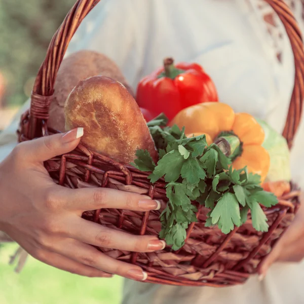 Unrecognizable woman holding basket full of vegetables and bread — Stock Photo, Image
