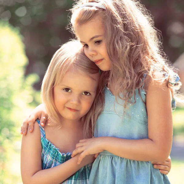 Outdoor portrait of two embracing cute little girls — Stock Photo, Image