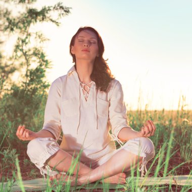 Yeşil çimlerde yoga yapan kadın.