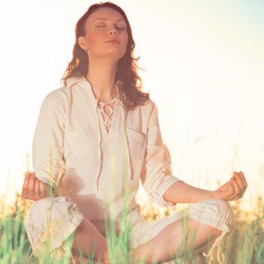 Yeşil çimlerde yoga yapan kadın.