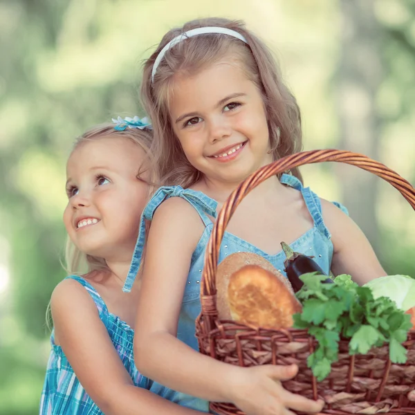 Zwei kleine Mädchen mit einem Korb mit Bio-Lebensmitteln — Stockfoto