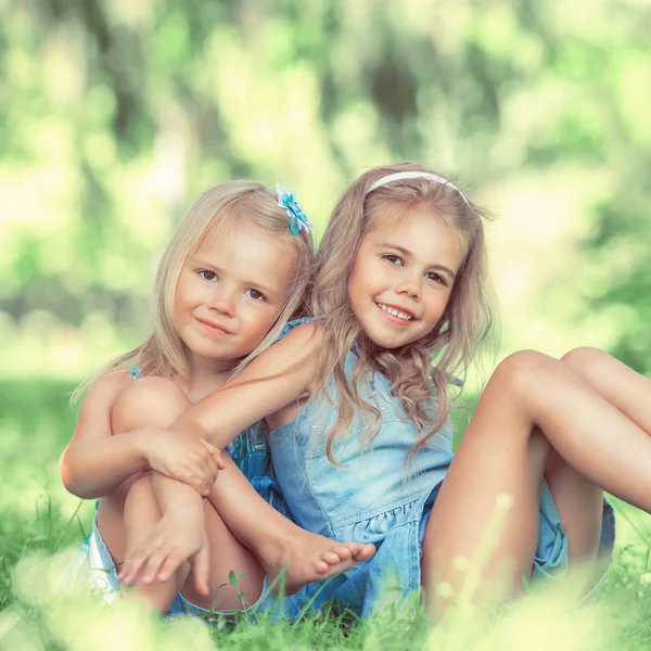 Duas meninas bonitos no gramado no parque — Fotografia de Stock