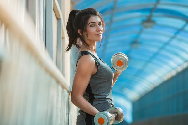 Athletic woman pumping up muscles — Stock Photo, Image