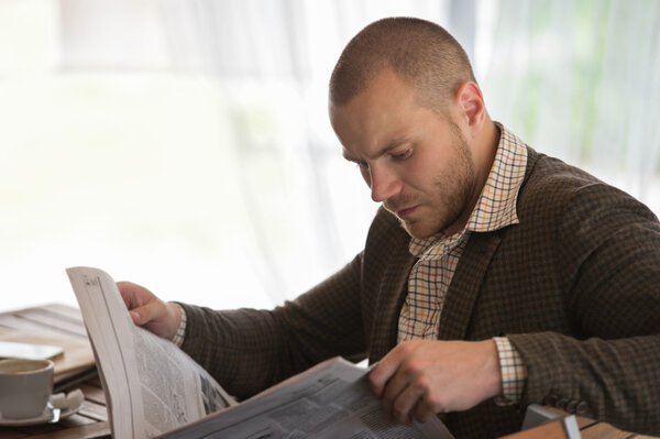 Businessman reading newspaper in cafe