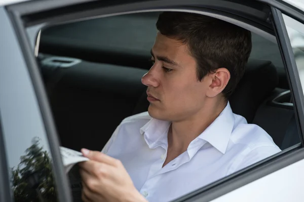 Geschäftsmann liest Zeitung im Auto — Stockfoto