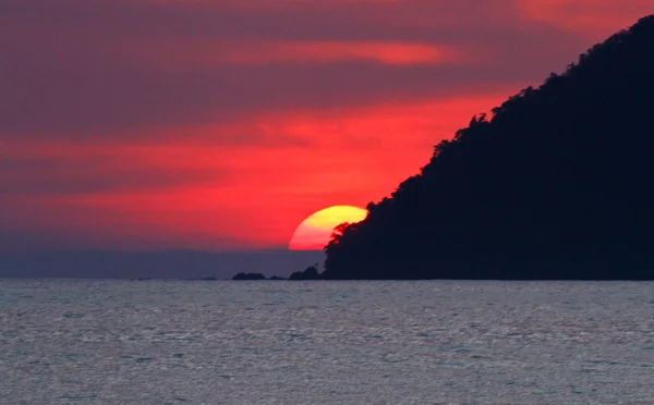 島の背後に夕日 ロイヤリティフリーのストック画像