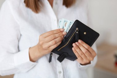 Beyaz gömlekli, siyah deri cüzdanlı, banknotlu, tasarruf eden bir kadın..