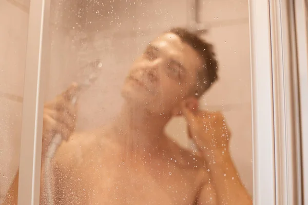 성인검은 머리의 남자가 샤워를 하면서 안개가 뒤에서 마시며 — 스톡 사진