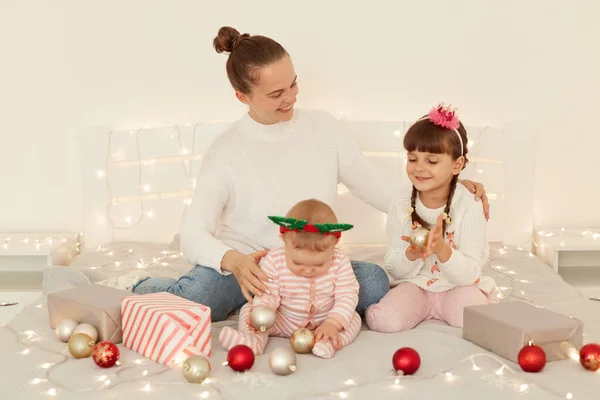 カジュアルな服装の子供たちと笑顔の正の母親の肖像 ベッドに座って 大晦日の間に一緒に時間を過ごす 冬の休日を祝う — ストック写真