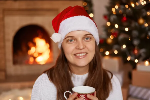 Улыбающаяся Молодая Белая Женщина Белом Свитере Шляпе Санта Клауса Сидящая — стоковое фото