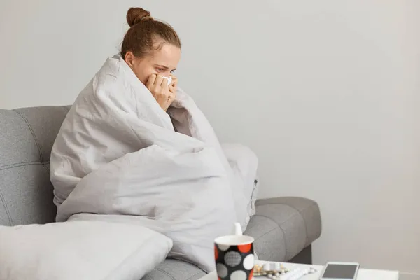 室内拍摄不健康的女人 头发缠在沙发上 裹着毯子 在寒冷的秋天感冒 流鼻涕 感觉很糟 — 图库照片