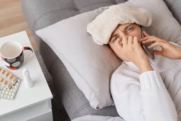 Unhealthy Woman Towel Her Forehead Swearing White Sweater Lying Sofa — Stock Photo, Image