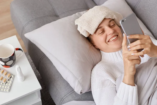 Glimlachende Gelukkige Vrouw Met Behulp Van Mobiele Telefoon Terwijl Ziek — Stockfoto