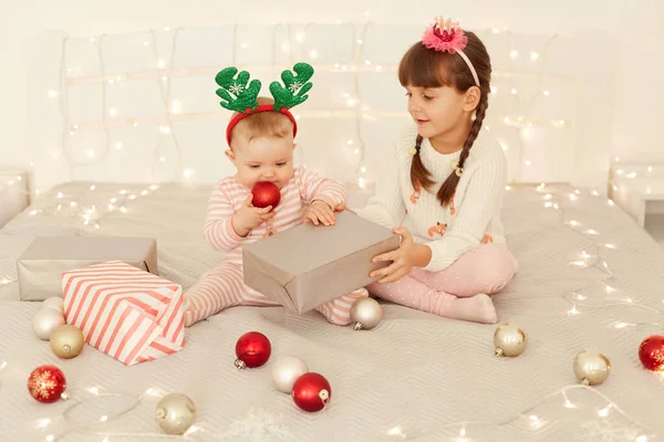 Внутренний Снимок Счастливых Позитивных Детей Сидящих Кровати Рождественскими Безделушками Гирляндами — стоковое фото