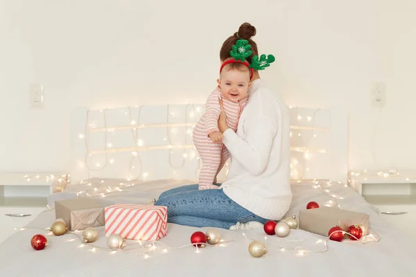 Портрет Матери Обнимающей Младенца Сидящей Кровати Рождественскими Безделушками Подарочными Коробками — стоковое фото