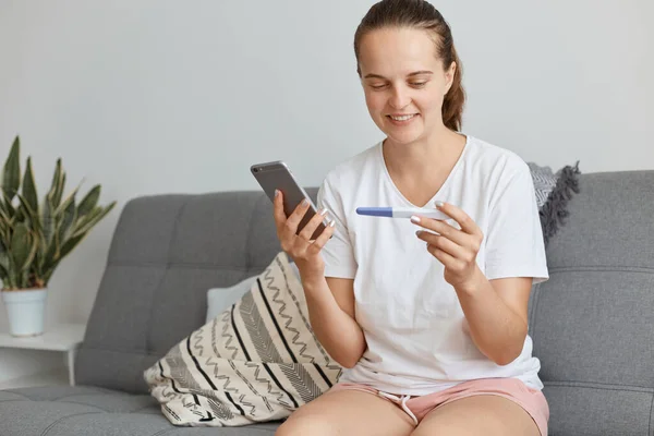 Ellerinde Hamilelik Testi Cep Telefonuyla Koltukta Otururken Rahat Bir Şekilde — Stok fotoğraf