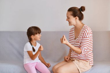 Kadın, profesyonel fizyoterapist, tatlı bir çocukla konuşma bozuklukları üzerinde çalışırken gri koltukta oturan, örgülü çocuk, konuşma yetisini geliştirmek için dil dersi alıyor..