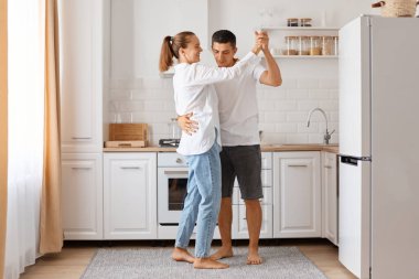 Güzel romantik çift mutfakta dans ediyor, birbirlerine sarılıyorlar, çocuklar uyurken birlikte vakit geçiriyorlar, günlük kıyafetlerini giyiyorlar..