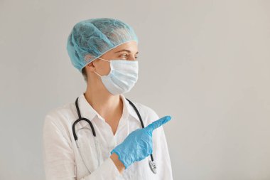 Tıbbi başlık, eldiven, ameliyat maskesi ve cübbesi takan kadın doktorların promosyon metni ya da ön parmağıyla reklamınızı gösteren yatay görüntüsü..