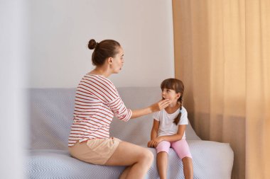 Küçük bir kızla çalışan genç bir kadın konuşma terapistinin kapalı çekimleri, gündelik kıyafet giyen insanlar, pencerenin yanındaki koltukta oturup ses ve kelimelerin nasıl telaffuz edileceğini gösteriyorlar..