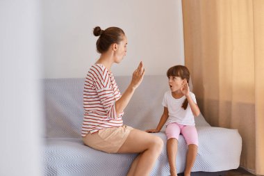 Kadın konuşma patolojistinin küçük bir kızdan ders aldığı yatay çekim pencerenin yanındaki koltukta oturan insanlar, genç bir kızın sesleri telaffuz etmeyi öğrendiği terapi seansı..