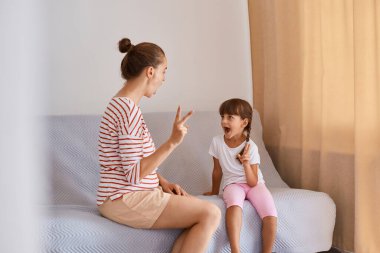 Küçük bir kızla birlikte çalışan kadın profesyonel konuşma terapistinin portresi, konuşmayı geliştirmek için dil dersi alması, günlük tarz kıyafetler giyen insanlar, pencerenin yanındaki koltukta oturan insanlar.
