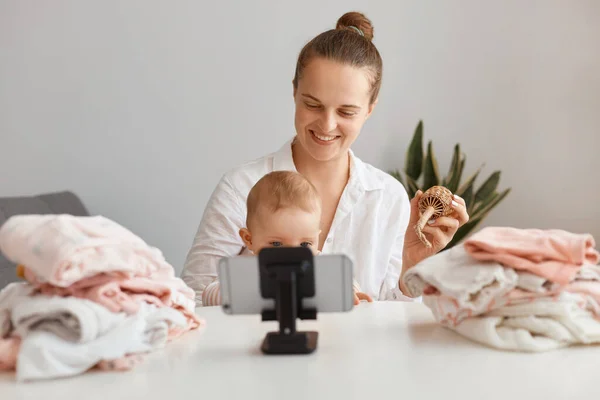 어머니 블로거 가아기를 데리고 식탁에 라이브 스트림 방송을 전화를 삼각대에 — 스톡 사진