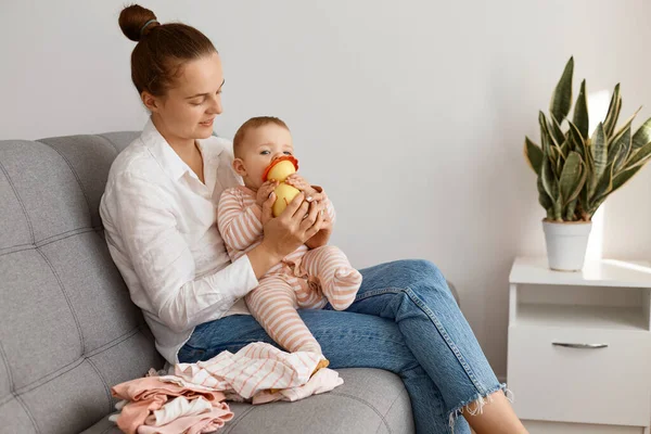 Siyah saçlı, siyah saçlı, günlük giysiler giyen, öksürük içinde bebeğiyle oturan, çocuk ısıran, hafta sonu çocuğuyla vakit geçiren bir kadın..