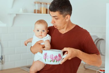 Şok olmuş bir babanın küçük kızını ve tencereyi elinde tutarken, kahvaltı hazırlarken, şaşkınlık ve şaşkınlık içerisindeyken, evde çocuğa yiyecek bir şey olmadığını fark ederken..