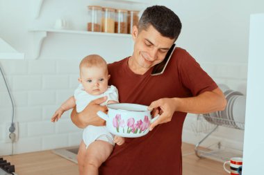 Kapalı alanda gülümseyen siyah saçlı bir babanın cep telefonuyla konuşması, küçük kızını kucağına alıp esrar içmesi, çocuğuna bakması, babalık izninde olması..